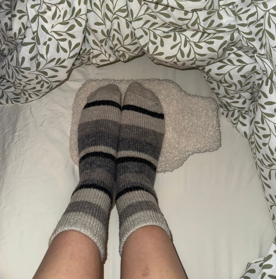 Feet in striped socks on a hot water bottle under a duvet.