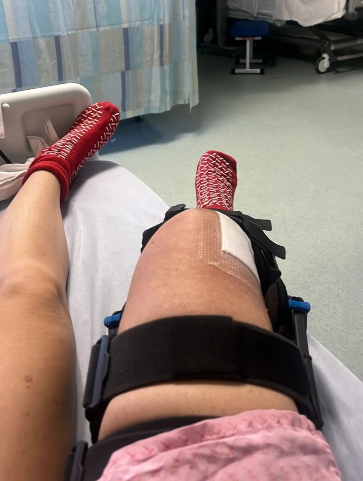 A person's leg in a brace in a hospital bed.
