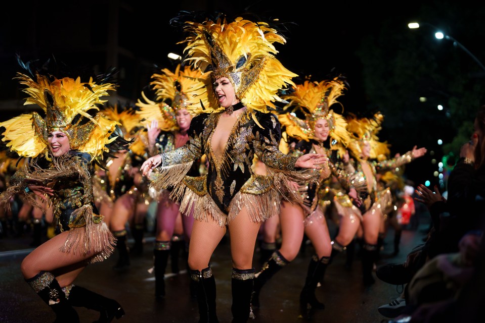 Carnival dancers in elaborate gold and black costumes perform.