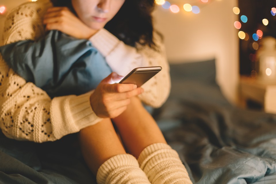 Young woman using smartphone in bed.