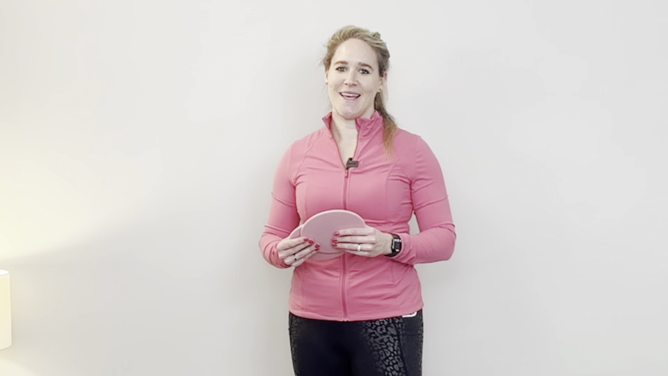 Personal trainer holding two pink slider discs.