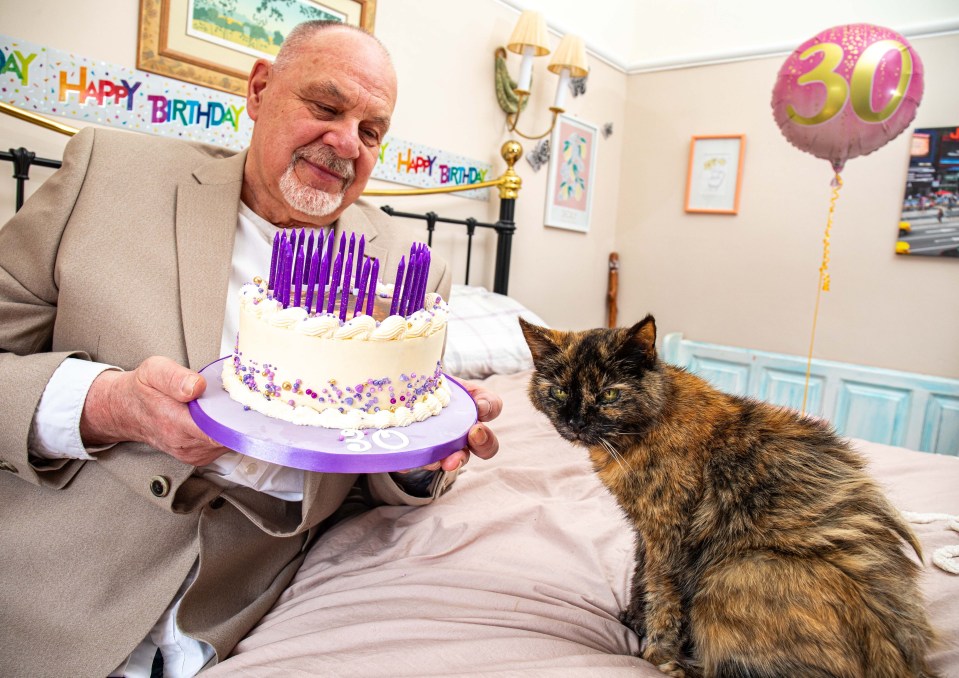 A man holding a 30th birthday cake for his cat.