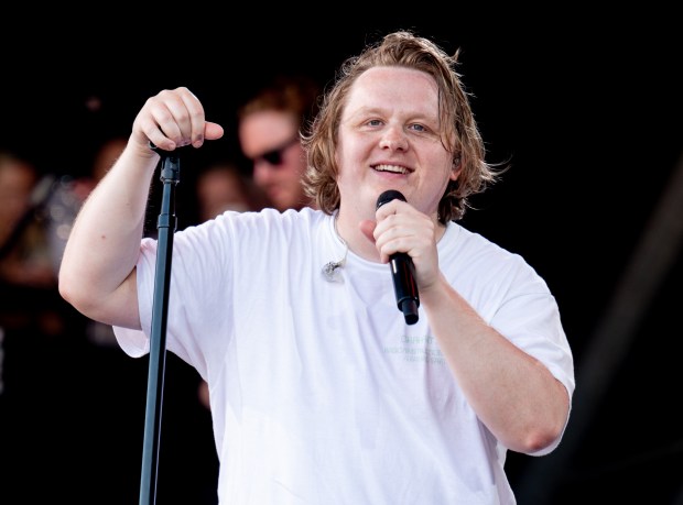 a man in a white shirt is singing into a microphone