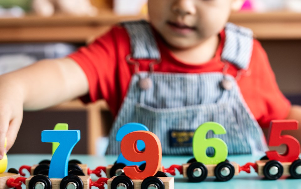Toddler playing with wooden number train toy.