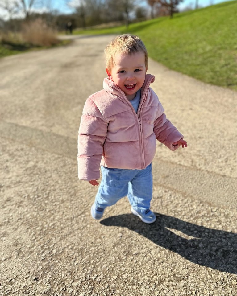 Toddler in pink jacket walking on a path.