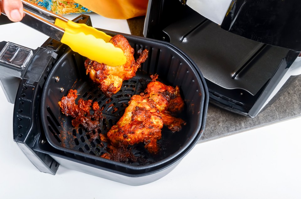 Air fryer chicken being removed with tongs.