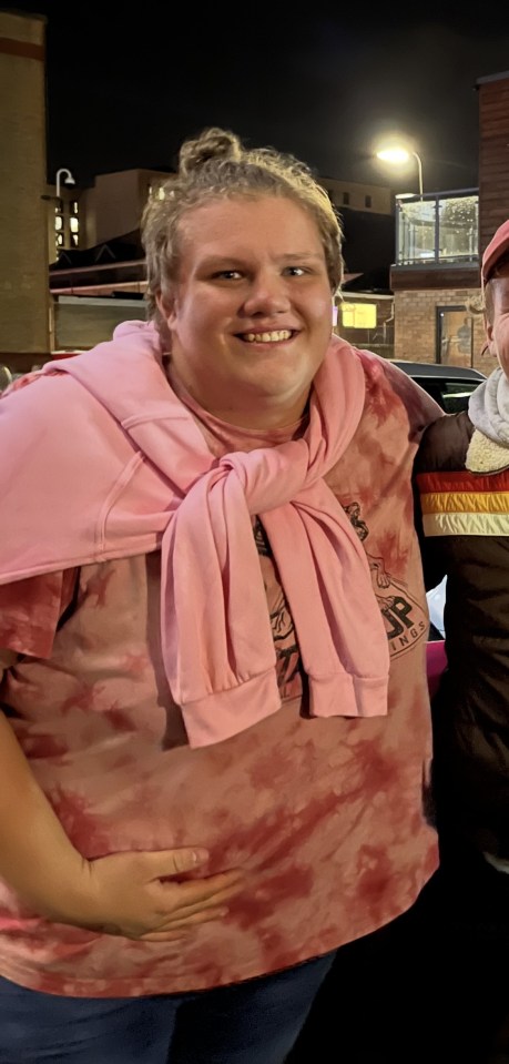 Photo of a young man wearing a pink sweatshirt over a tie-dye shirt.