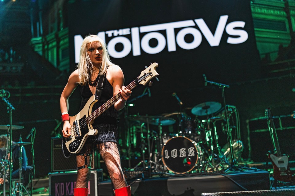 A woman playing bass guitar on stage at a Molotovs concert.