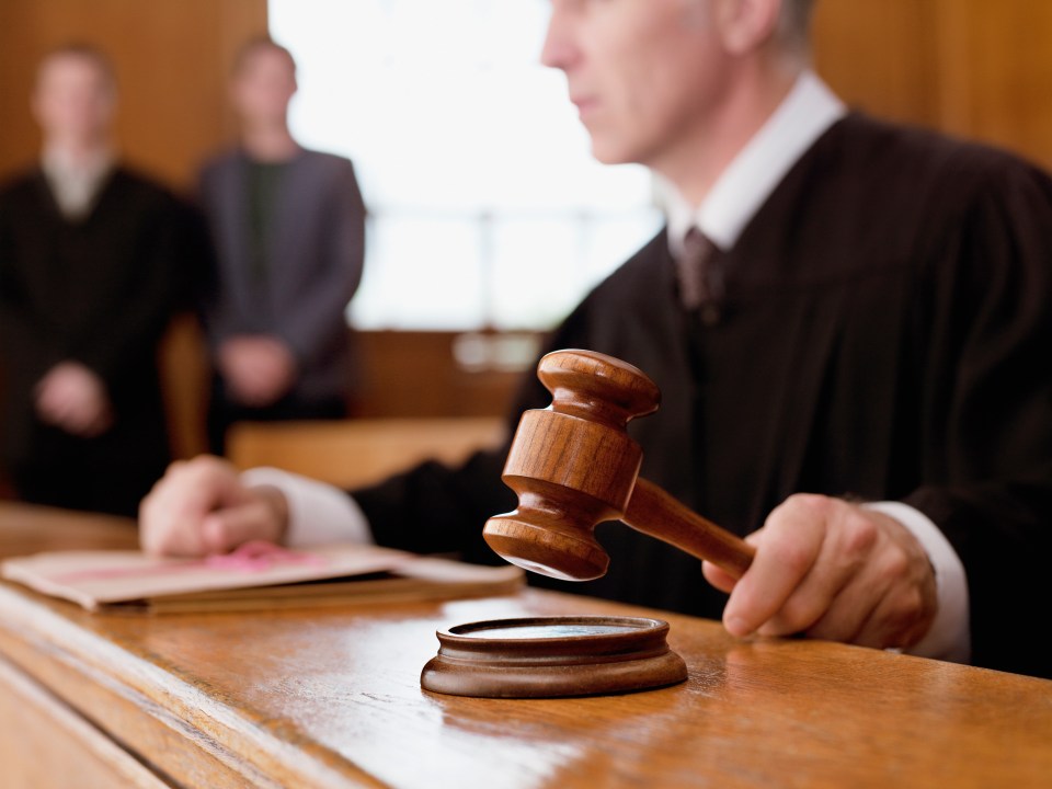Judge holding a gavel in a courtroom.