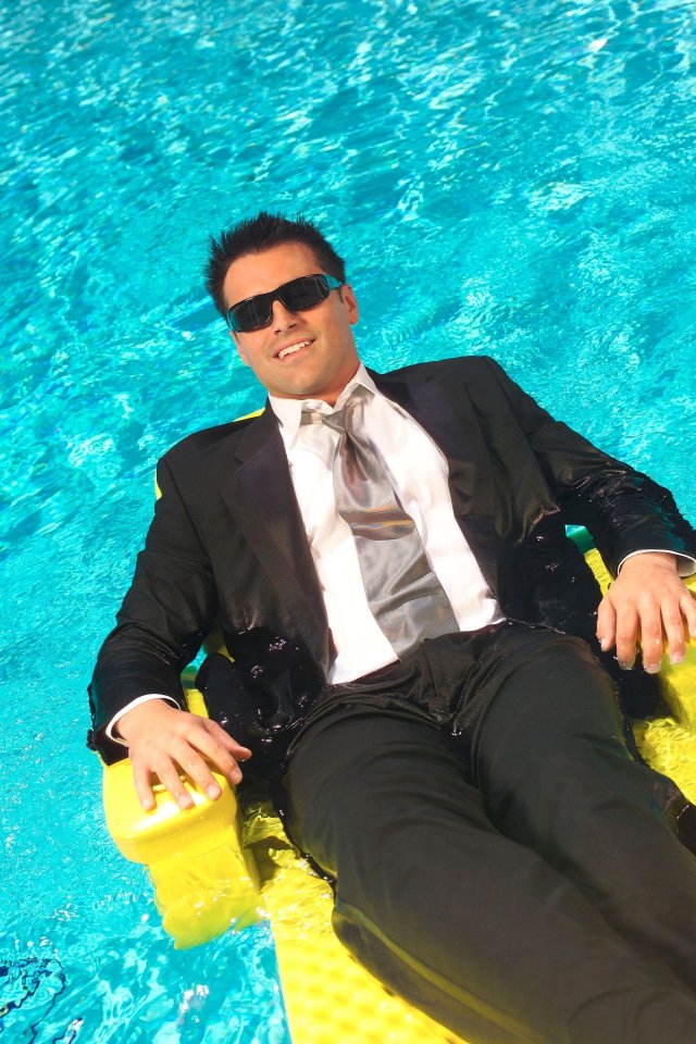 Man in suit and sunglasses relaxing in a pool.