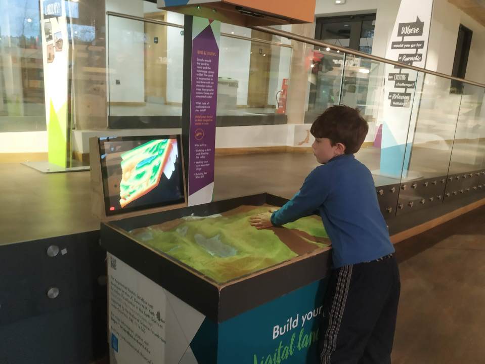 Boy interacting with an augmented reality sandbox.