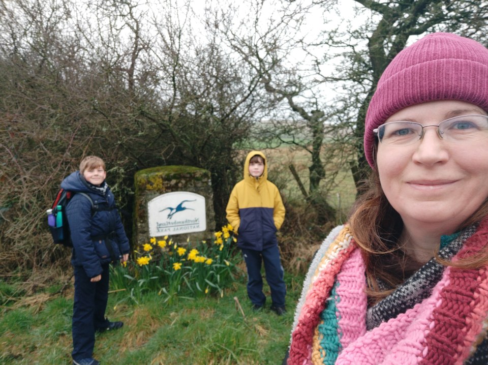 Family by Northumberland National Park sign with daffodils.