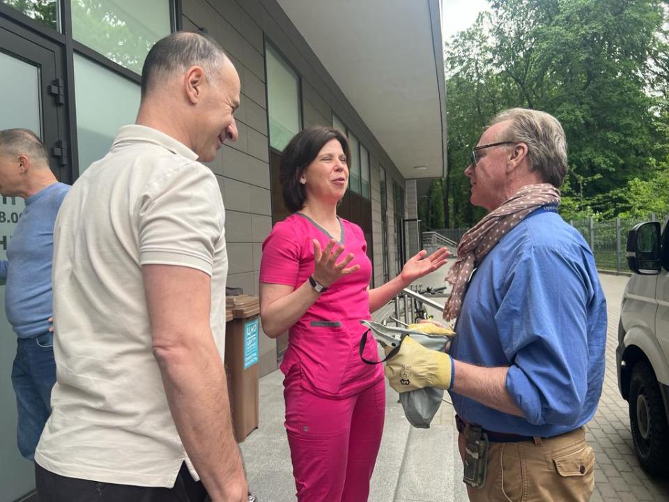Three people talking outside a building.
