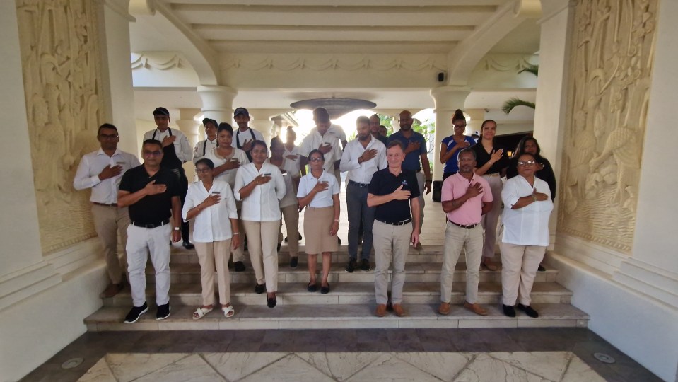 Group of people standing on steps, hands over hearts.
