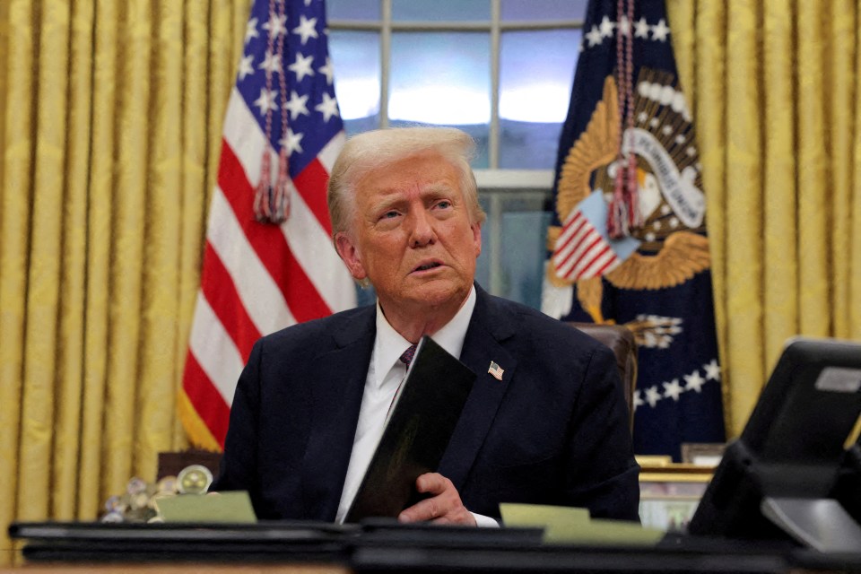 President Trump signing documents in the Oval Office.