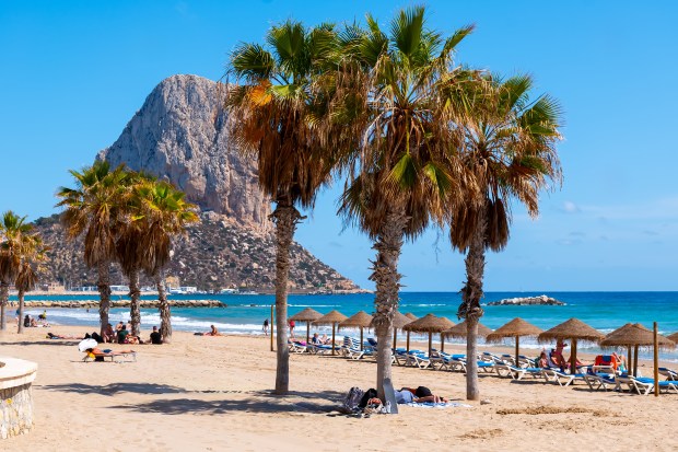Beach in Calpe, Spain, with a large rock formation in the background.