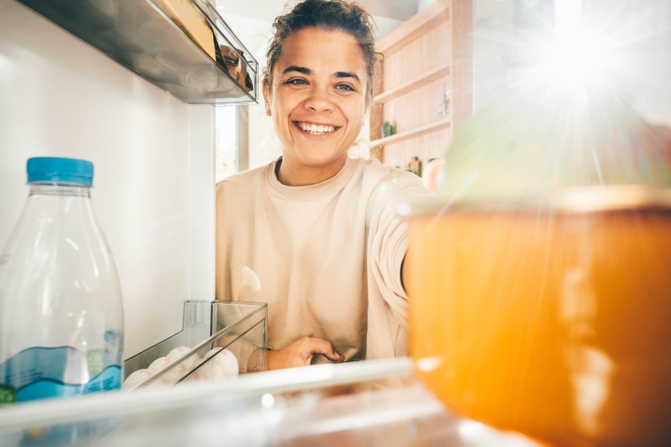 Smiling woman taking food from refrigerator.