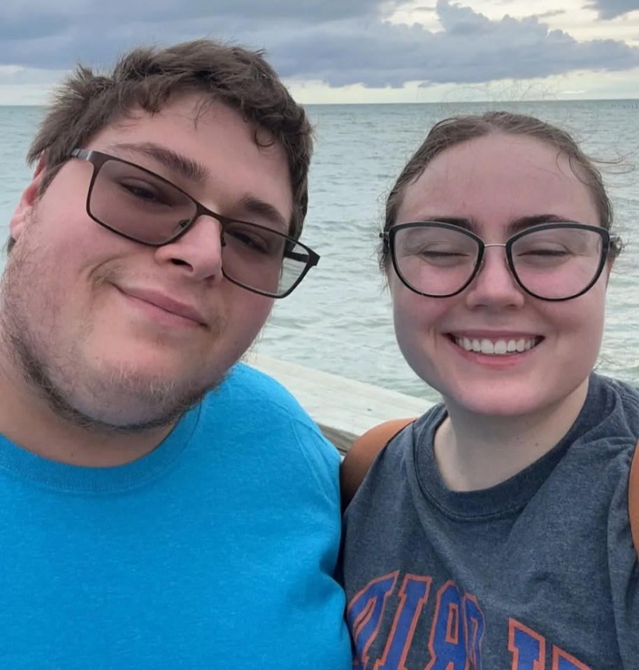 A couple smiling for a selfie by the ocean.