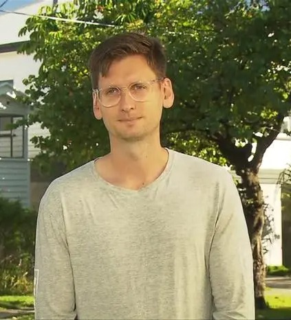 Man standing outside house damaged by party.