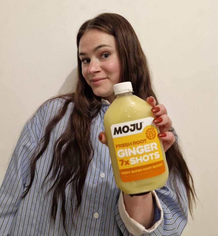 Woman holding a bottle of Moju ginger shots.