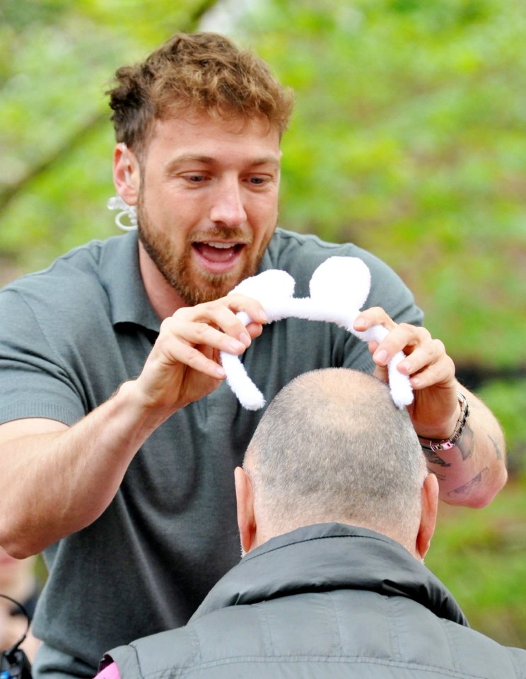 Sam Thompson placing bunny ears on a man's head during a live television segment.