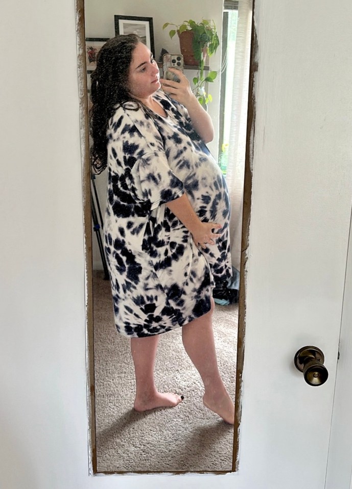 Mirror reflection of a pregnant woman in a tie-dye dress.