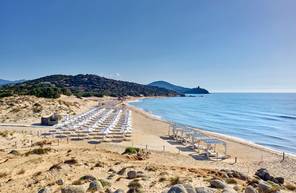 Sardinia beach with rows of white umbrellas and cabanas.