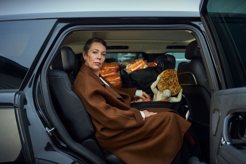 Olivia Colman in a car with bags of Warburtons crumpets.
