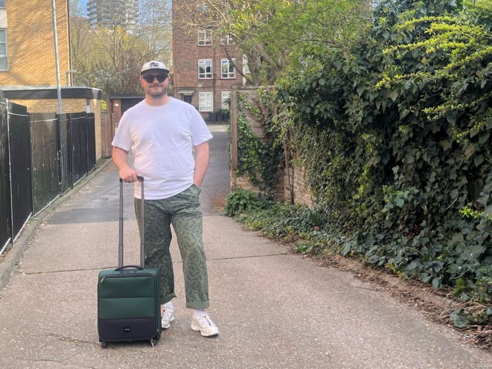 Man pulling a dark-green Antler underseat suitcase down a driveway.