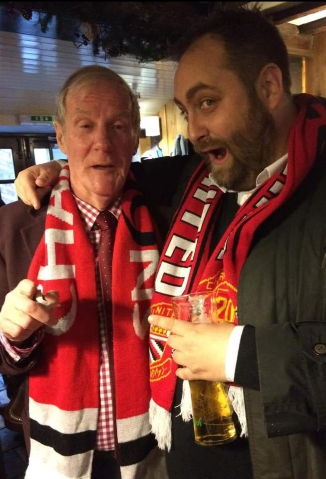Two men wearing Manchester United scarves.
