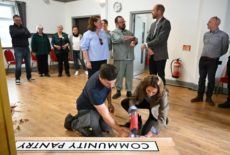 Catherine, Princess of Wales, using a nail gun to build a sign for a community pantry.