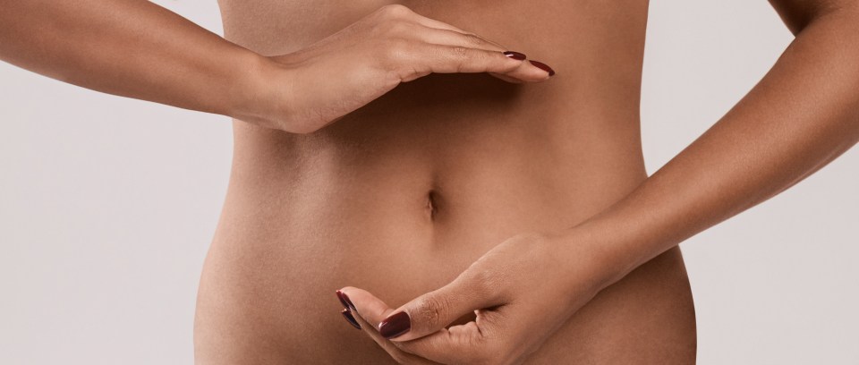 Woman's hands gently cradling her abdomen.