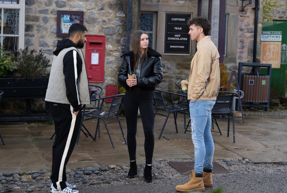 Three people standing outside a cafe, talking.