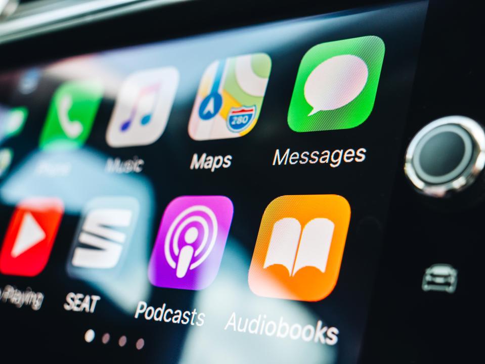 Apple CarPlay screen showing various app icons including Phone, Music, Maps, Messages, Podcasts, and Audiobooks.