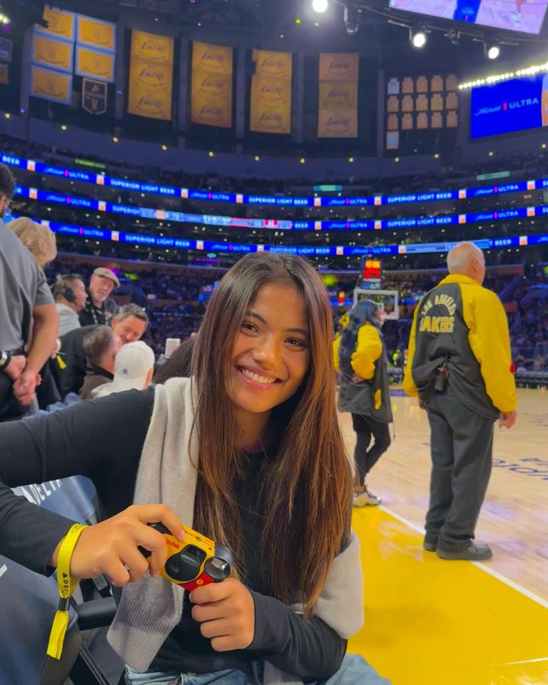 Woman holding a camera at a basketball game.
