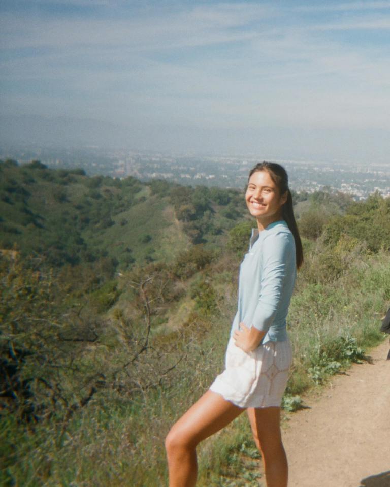 Emma Raducanu on a hike overlooking a city.