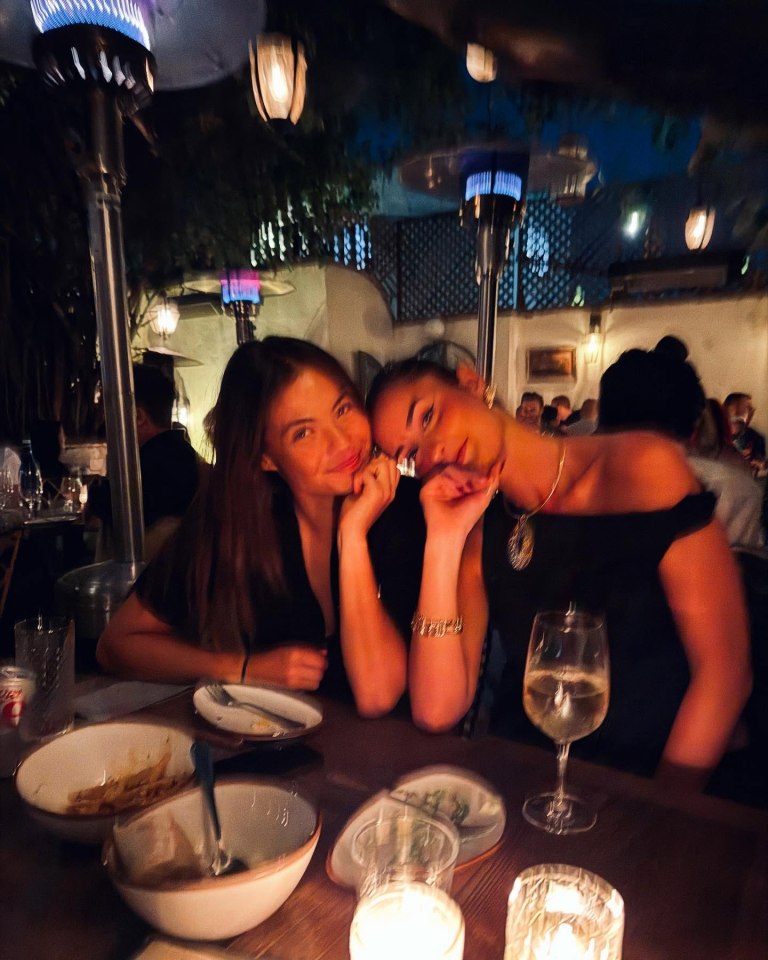 Two women sitting at a table outdoors at night.