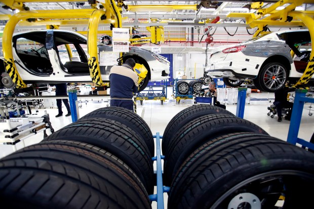 Workers installing tires on cars on an assembly line.