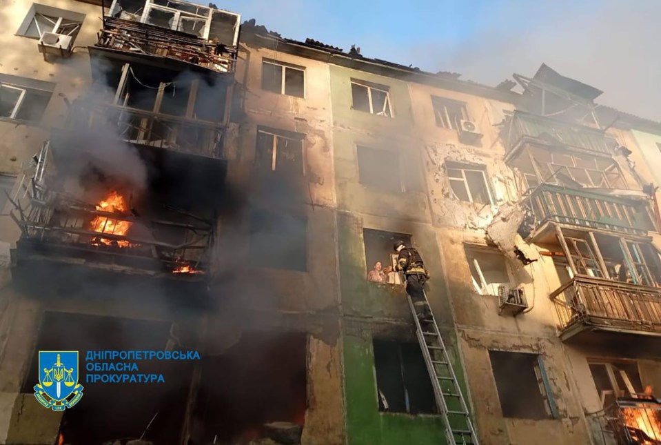 Firefighters rescuing a person from a damaged apartment building after a Russian strike.