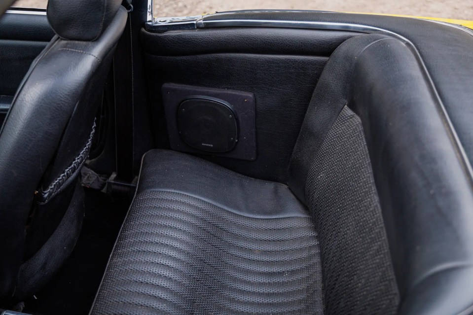 Rear seat of a 1977 Triumph Stag with a Kenwood speaker.