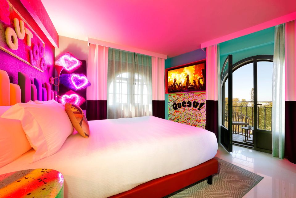 Hard Rock Marbella hotel room with a bed, neon hearts, and a balcony view.
