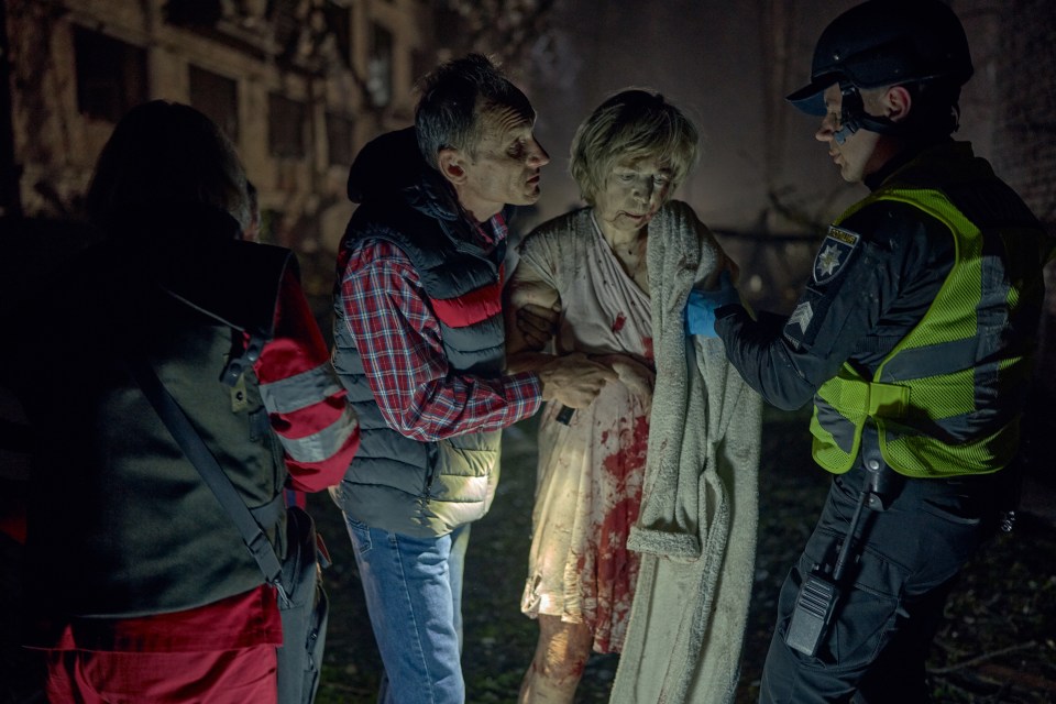 Rescuers aiding a bloodied civilian after a missile strike.