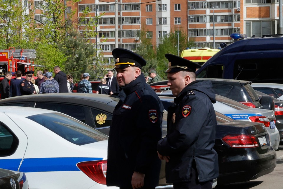 Two police officers standing in front of parked cars.