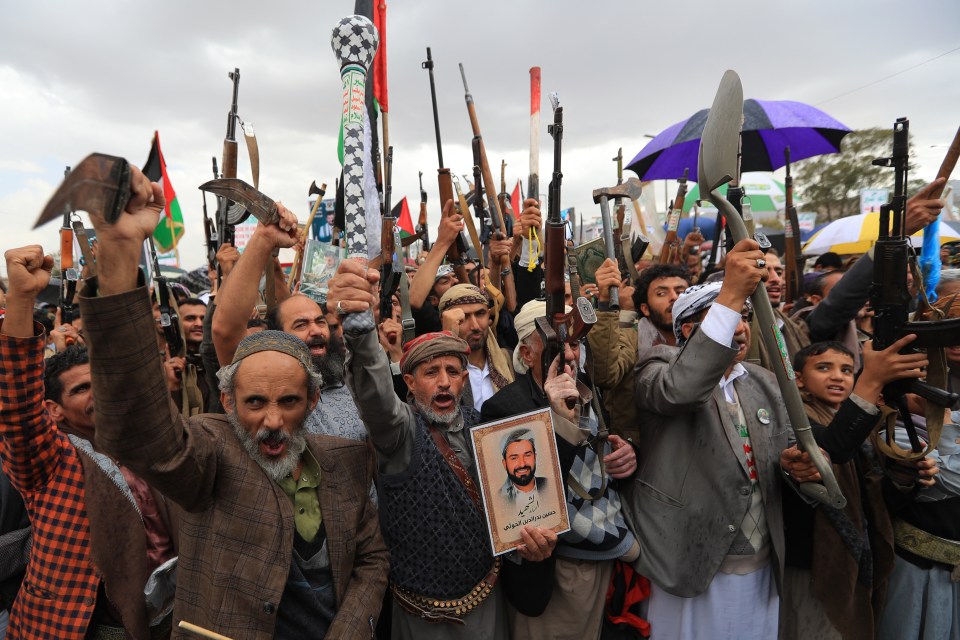 Crowd of Houthi rebels in Sanaa holding weapons and a portrait during Quds Day commemorations.
