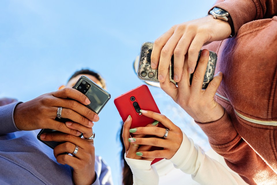Three young adults using smartphones outdoors.