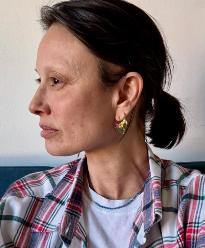 Woman wearing colorful earrings and a plaid shirt.