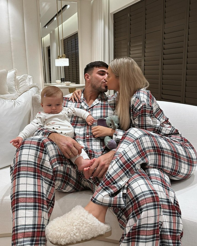 Couple kissing with their baby on a couch.