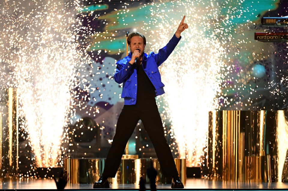 Olly Murs performing on stage with fireworks.