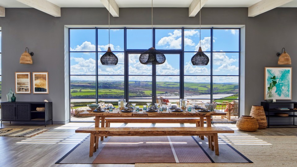 A four-bedroom house with a large window overlooking a scenic view, a dining table set for a meal, and various home decor items.