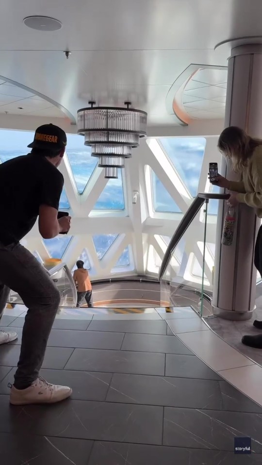 Passengers on a cruise ship taking photos of large waves through the ship's windows.
